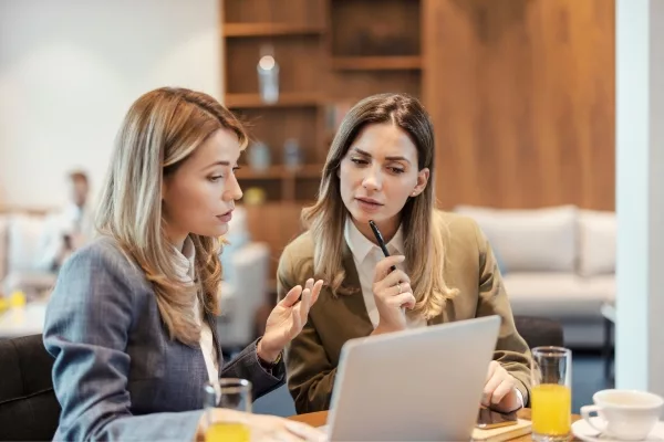 Two women reviewing work together on a laptop