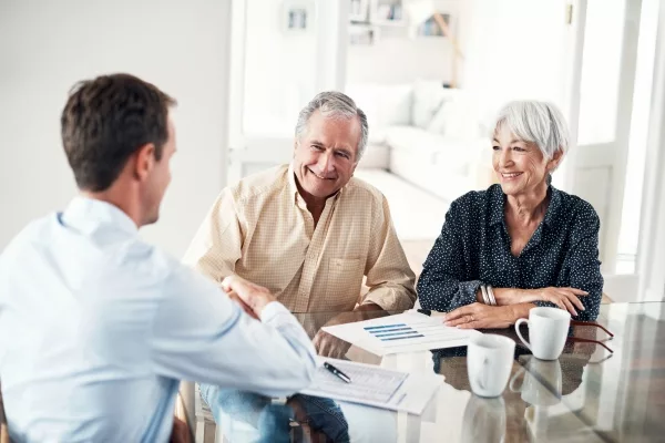 Advisor meeting with a smiling older couple at a table with charts