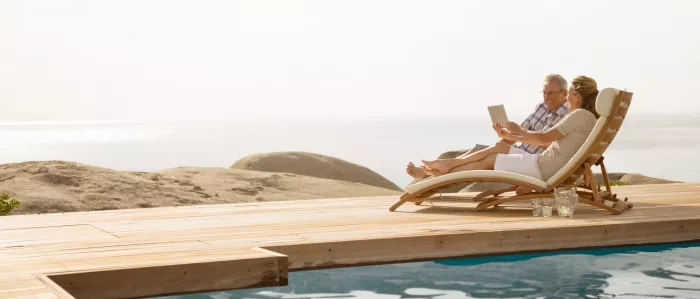 Retired couple relaxing on lounge chairs on a deck by the water